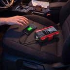 Illustration: red jump starter charging a phone over USB on a car seat