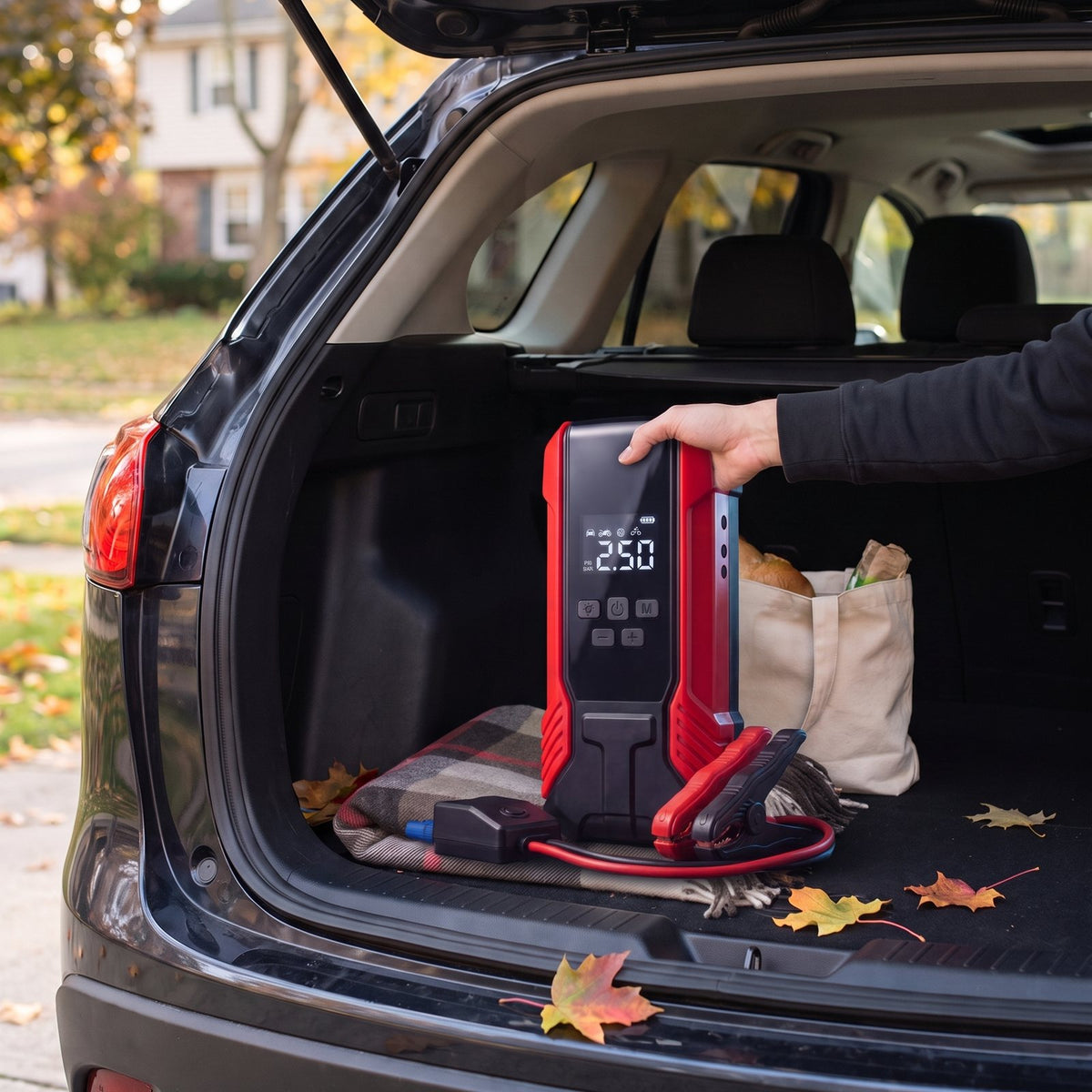 Illustration: red jump starter and its clamps in an SUV trunk